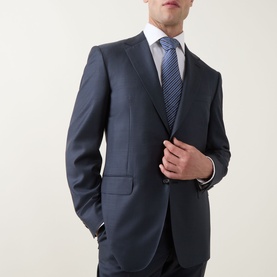 Model wearing Canali D6 Griz Solid Two-Piece Suit in dark blue, styled with a white shirt and blue striped tie.