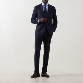 Model wearing Canali dark blue wool suit, styled with light blue shirt, navy tie and black leather loafers