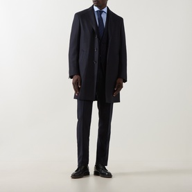 Model wearing Canali dark blue wool suit styled with a matching overcoat, light blue shirt, navy tie and black leather shoes.