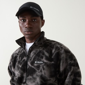 Model with Columbia Silver Ridge&trade; IV Cap in black, styled with a matching black Columbia full-zip fleece jacket.