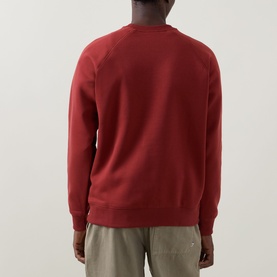 Model wearing Columbia crew neck sweatshirt in Red Oxide, rear view, styled with khaki trousers