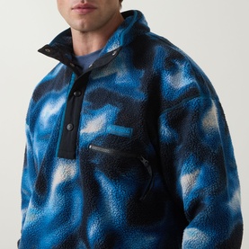 Model wearing Columbia Helvetia&trade; II Printed Half Snap Fleece in Phoenix Blue abstract camo print, with chest zip pocket and snap collar detail.