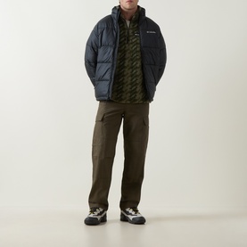 Model wearing Columbia Helvetia II Printed Half Snap Fleece in Stone Green Twills, styled with dark puffer jacket, brown cargo trousers and trail