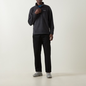 Model wearing Columbia black fleece half-zip pullover with blue collar detail, styled with black trousers and grey trainers