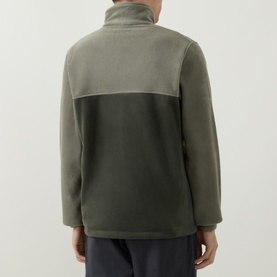 Model wearing Columbia fleece in Stone Green, two-tone colourblock design with high neck, back view