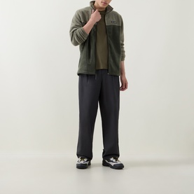Model wearing Columbia Stone Green fleece zip-up, styled with dark wide-leg trousers and monochrome trainers.