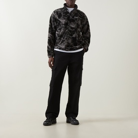 Model wearing Columbia fleece in Black Icepeaks camo print with black cargo trousers and dark trainers.
