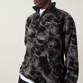 Model wearing Columbia fleece in Black Icepeaks, half-zip funnel neck, all-over dark marble print, paired with white T-shirt.