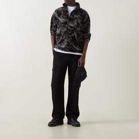 Model wearing Columbia Black Icepeaks fleece pullover with black cargo trousers, white tee underneath, and black cap in hand.