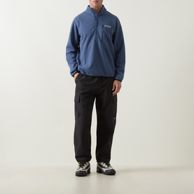 Model wearing Columbia Sweater Weather II Fleece Jacket in Dark Mountain blue, half-zip, styled with black cargo trousers and hiking trainers