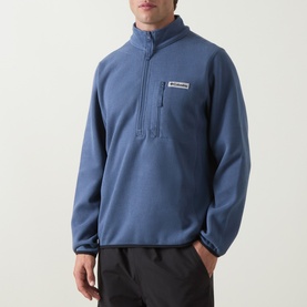 Model wearing Columbia Sweater Weather II Fleece Jacket in Dark Mountain blue, half-zip fastening, zipped chest pocket, styled with black trousers.
