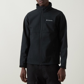 Model wearing Columbia CSC Basic Logo T-Shirt in black with white chest logo print, styled with dark trousers.