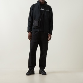 Model wearing Columbia Ascender&trade; Hiking Softshell Jacket in black with zip fastening, styled with black cargo trousers and crossbody bag.