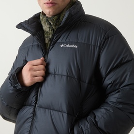 Model wearing Columbia Pike Lake II Puffer Jacket in black, showing quilted front zip detail and stand collar with camo inner layer visible.