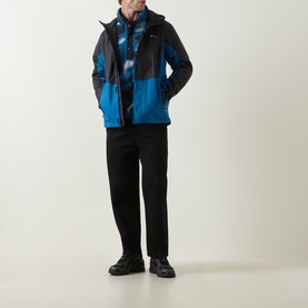 Model wearing Columbia Pouring Adventure&trade; III Waterproof Hiking Jacket in Black/Phoenix Blue colourblock, styled with black trousers and trainers.