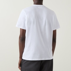Model wearing Columbia CSC Basic Logo T-Shirt in white, rear view, round neck, short sleeves, paired with dark trousers.
