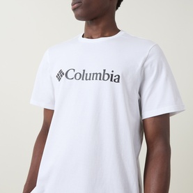 Model wearing Columbia CSC Basic Logo T-Shirt in white, round neck with chest logo print, short sleeves visible.