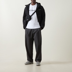 Model wearing Columbia CSC Basic Logo T-Shirt in white, styled with black zip-up hoodie, black trousers, and grey trainers, with a small crossbody