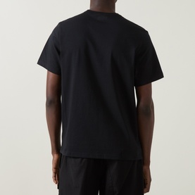 Model wearing Columbia CSC Basic Logo T-Shirt in black, back view, with high-neck dark overshirt layered on top.