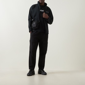 Model wearing Columbia CSC Basic Logo T-Shirt in black, styled with black jacket, cargo trousers, and black shoes.