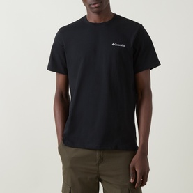 Model wearing Columbia CSC Logo Back Graphic T-Shirt in black, short sleeves, round neck, small chest logo, styled with khaki trousers.