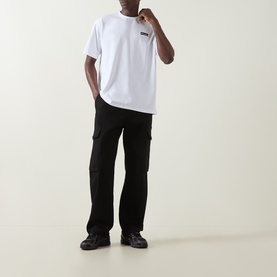 Model wearing Columbia white cotton T-shirt with black cargo trousers and dark trainers.