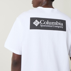 Model wearing Columbia white cotton T-shirt, back view showing black rectangular logo graphic with Columbia Sportswear Company branding.