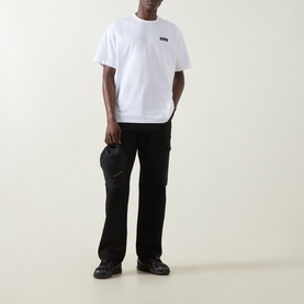 Model wearing Columbia white cotton T-shirt with small chest logo, styled with black cargo trousers and black boots.