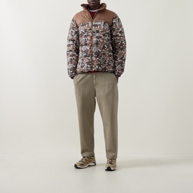 Model wearing Columbia outerwear jacket in Fossil/Camo print with brown yoke, styled with taupe trousers and grey trainers