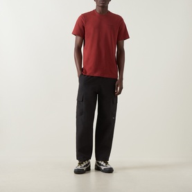 Model wearing Columbia Red Oxide cotton T-shirt with black cargo trousers and multi-coloured trainers.