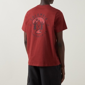 Model wearing Columbia Red Oxide cotton T-shirt, back view showing circular mountain and tree graphic print, styled with black trousers.