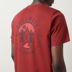 Model wearing Columbia T-shirt in Red Oxide, back view showing mountain and sun graphic print with Columbia Sportswear Co. 1938 branding.