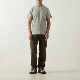 Model wearing Columbia CSC Outdoor Back Graphic T-Shirt in Safari green with olive cargo trousers and dark trainers.