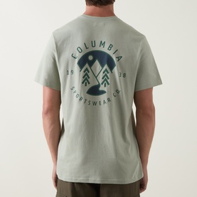 Model wearing Columbia CSC Outdoor Back Graphic T-Shirt in Safari green, showing circular mountain logo graphic on back, short sleeves, round neck.