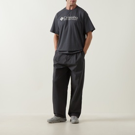 Model wearing Columbia CSC Retro Logo T-Shirt in Shark grey with black trousers and grey trainers