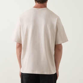 Model wearing Columbia CSC Retro Logo T-Shirt in Dark Stone, back view, relaxed fit, short sleeves, straight hemline, styled with black trousers.