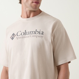 Model wearing Columbia CSC Retro Logo T-Shirt in Dark Stone, featuring large chest logo graphic and short sleeves
