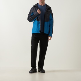 Model wearing Columbia Parons Logo Back Graphic T-Shirt in Collegiate Navy, styled with a blue colourblock hooded jacket and black trousers.