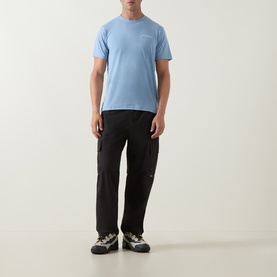 Model wearing Columbia Parons Logo Back Graphic T-Shirt in Rainy Day Heather blue, styled with black cargo trousers and trail trainers.