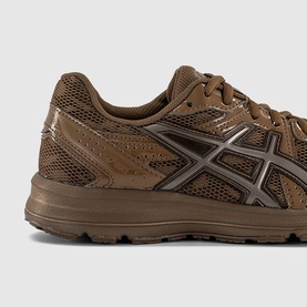 Asics trainer in brown, featuring mesh upper, silver chevron branding and brown rubber sole, close-up detail view.