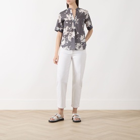 Model wearing Marc O Polo dark grey floral cotton blouse with white cropped trousers and black strappy flat sandals.