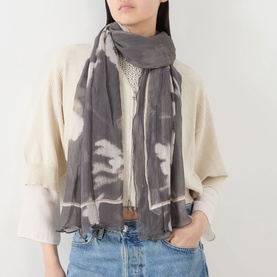 Model with Marc O Polo Pareo Printed Woven Scarf in dark grey multi, draped loosely over cream knit top and denim jeans