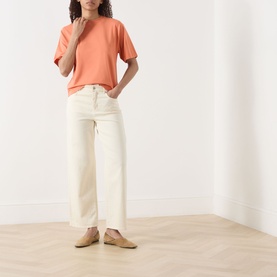Model wearing Marc O Polo Warm Orange T-shirt with wide-leg cream jeans and tan flat mules