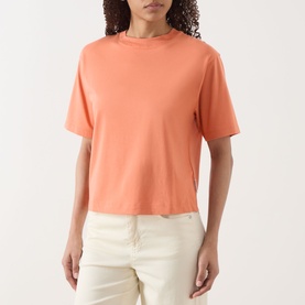 Model wearing Marc O Polo warm orange relaxed-fit T-shirt with crew neck and short sleeves, styled with cream trousers.