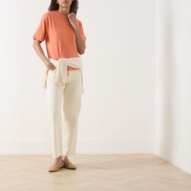 Model wearing Marc O Polo Warm Orange relaxed T-shirt, styled with cream trousers tied at waist and tan mules.