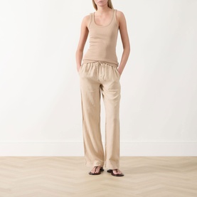 Model wearing Marc O Polo Solid Logo Tank Top in Sandpaper, ribbed scoop neck, styled with wide-leg beige trousers and black flat sandals