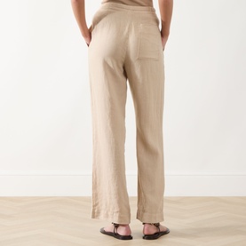 Model wearing Marc O Polo Linen Straight-Leg Trousers in Sandpaper, rear view showing patch pocket and clean straight hem, styled with black sandals