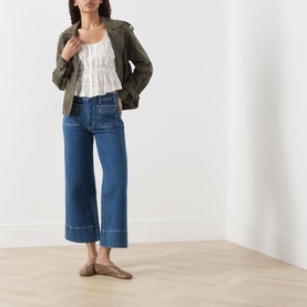 Model wearing Paige Jay Embroidered Blouse in Antique White with wide-leg blue jeans, olive jacket, and tan mules.