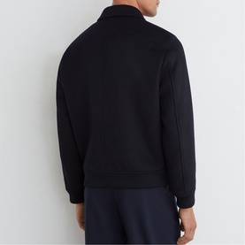 Model wearing Reiss blue zip-through jacket, back view, styled with navy trousers