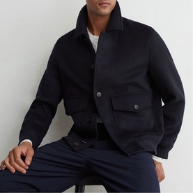 Model wearing Reiss blue wool-blend bomber jacket with chest pockets and button fastening, styled with navy trousers